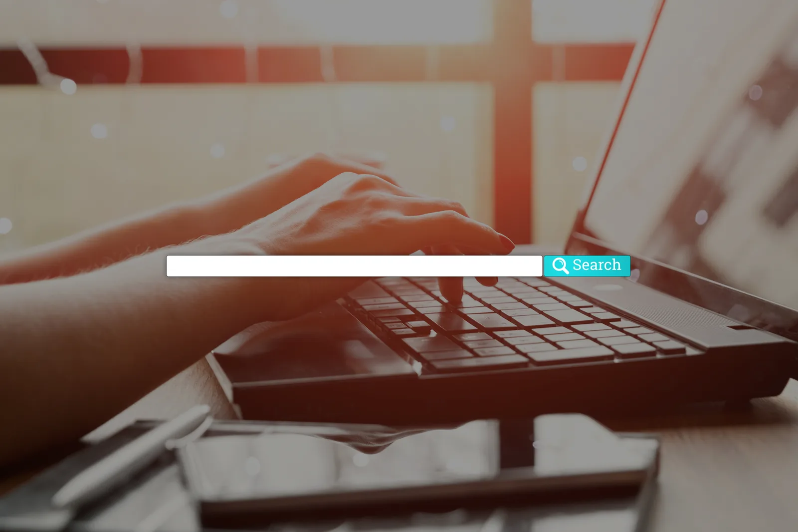 Hands typing a search into a laptop search bar