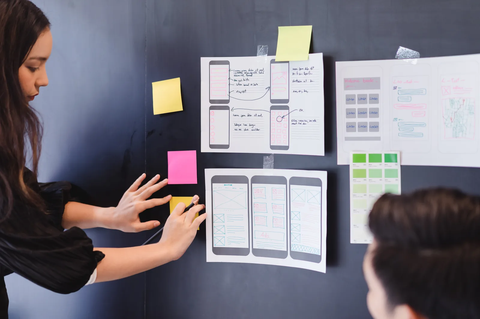 UX designer arranging website wireframes on a dark wall